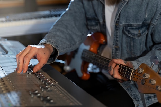 Foto gratuita vista lateral del hombre tocando la guitarra en el estudio.