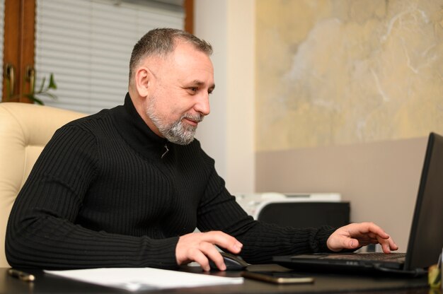 Vista lateral hombre trabajando en una computadora portátil