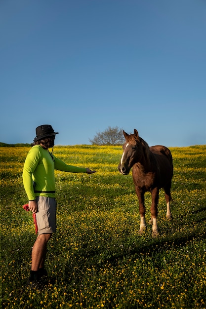 Foto gratuita vista lateral hombre tratando de alimentar a caballo