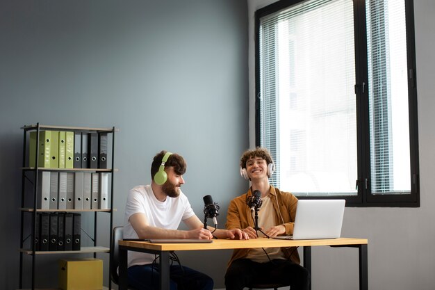 Vista lateral de hombres sonrientes grabando podcast