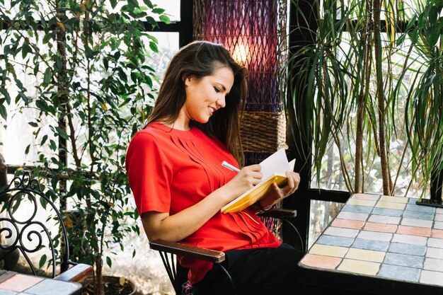 Vista lateral de un horario de escritura de la mujer joven en el diario