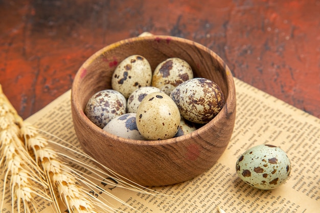 Vista lateral de los huevos frescos de granja dentro y fuera de una olla de madera en un periódico viejo sobre una mesa marrón