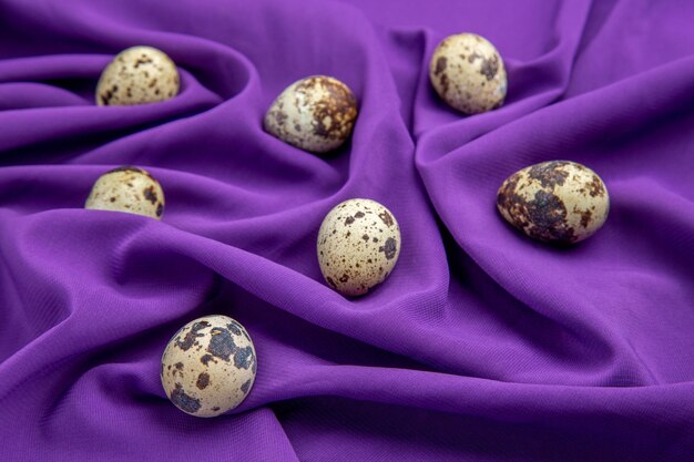 Vista lateral de huevos de granja orgánicos frescos en toalla violeta