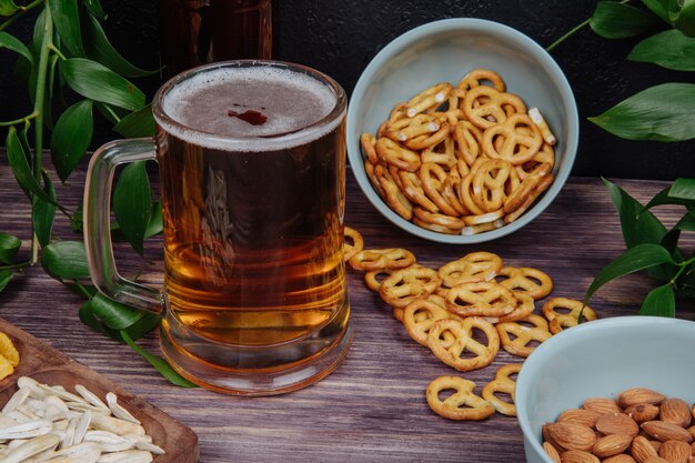 Vista lateral de una jarra de cerveza con mini pretzels en rústico
