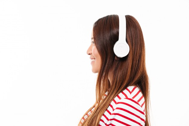 Vista lateral de una joven asiática en auriculares