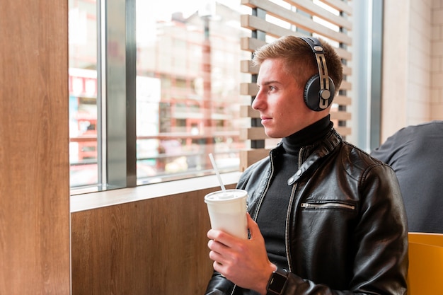 Vista lateral joven escuchando música con auriculares dentro