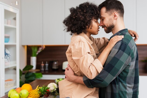 Vista lateral joven pareja abrazándose en la cocina