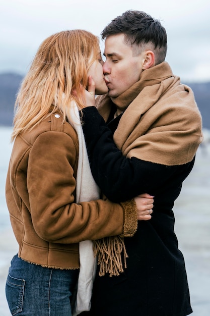 Foto gratuita vista lateral de la joven pareja besándose en invierno al aire libre