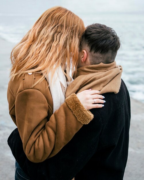 Vista lateral de la joven pareja besándose en invierno fuera