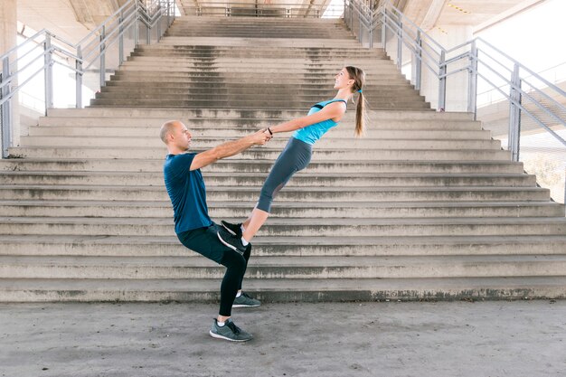 Vista lateral de la joven pareja deportiva haciendo ejercicio frente a la escalera