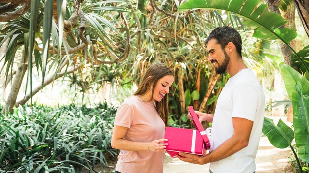 Vista lateral de un joven que muestra el regalo a su novia