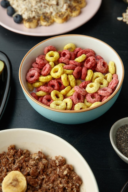 Vista lateral del juego de desayuno con cereales en un tazón de avena de plátano de nuez en un tazón y avena de lino de endrino de plátano en un plato con un tazón de semillas de chía sobre fondo negro