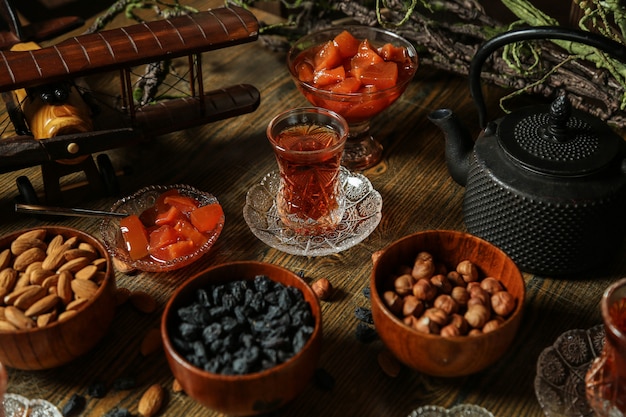 Vista lateral juego de té pasas almendras nueces mermelada de membrillo con té sobre la mesa