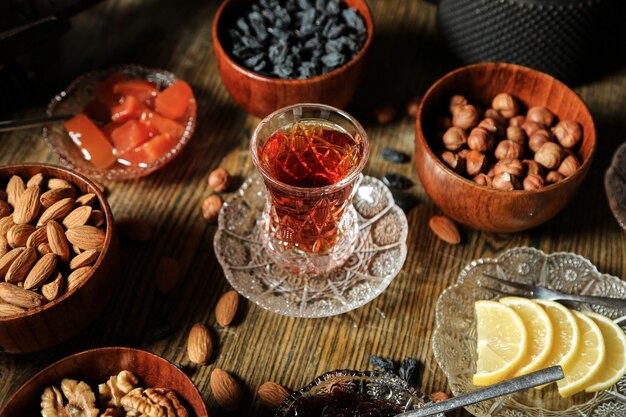 Vista lateral juego de té pasas almendras nueces mermelada de membrillo con té sobre la mesa