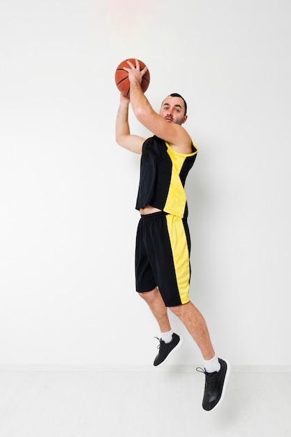 Foto gratuita vista lateral del jugador de baloncesto sumergiendo en el aire