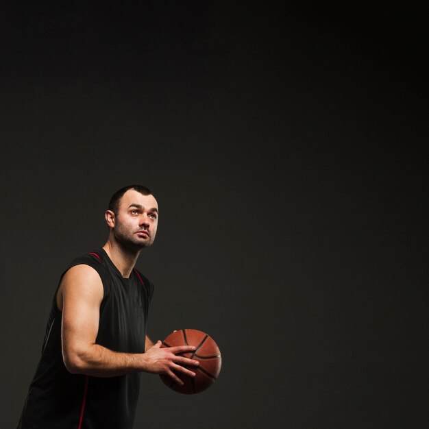 Vista lateral del jugador masculino con baloncesto con espacio de copia