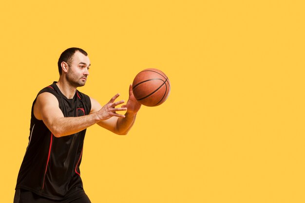 Vista lateral del jugador masculino lanzando baloncesto con espacio de copia
