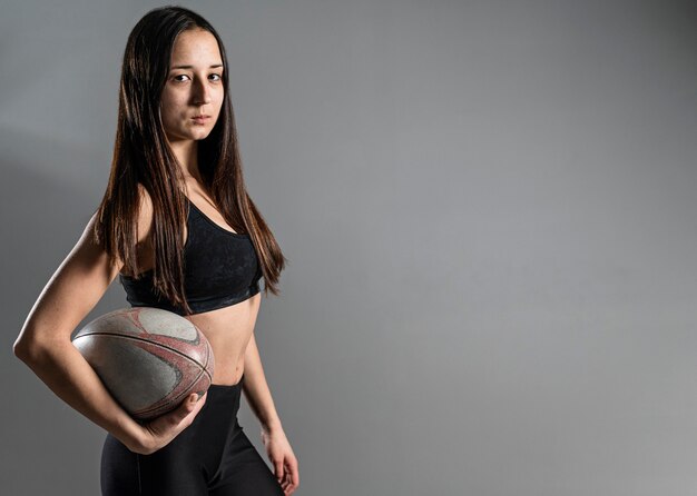 Vista lateral del jugador de rugby femenino posando con balón y espacio de copia