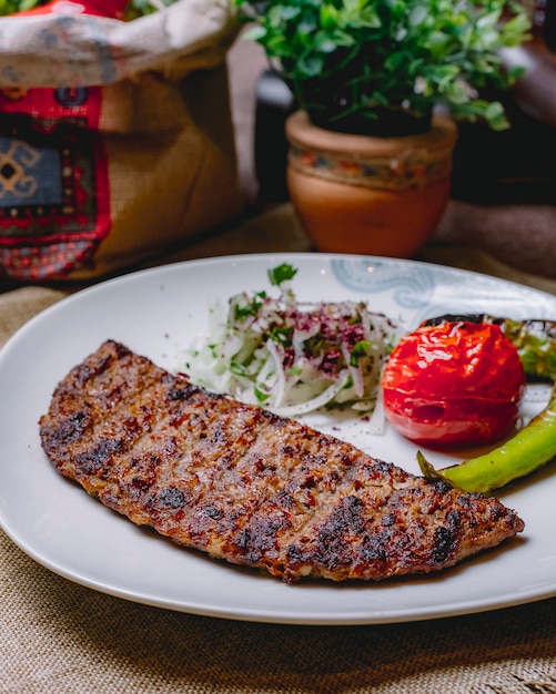 Vista lateral kebab con cebolla de tomate pimiento verde picante a la parrilla y verduras en un plato