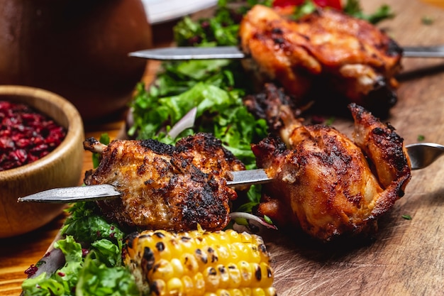 Vista lateral kebab de pollo con verduras cebolla roja maíz a la parrilla y agracejo seco sobre la mesa