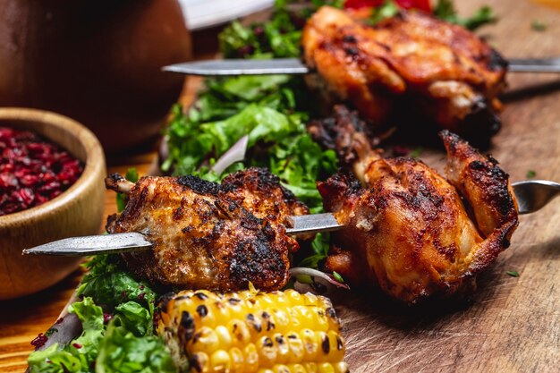 Vista lateral kebab de pollo con verduras cebolla roja maíz a la parrilla y agracejo seco sobre la mesa