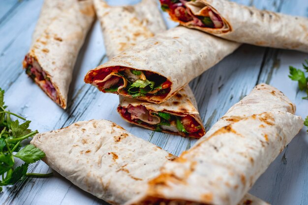 Vista lateral lahmacun con tomate verde cebolla roja y salsa en pita