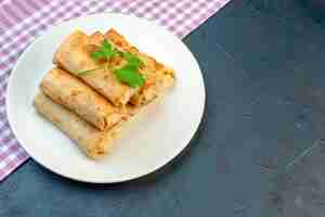 Foto gratuita vista lateral de lavash se envuelve en un plato con verde sobre una toalla despojada de color púrpura en el lado derecho sobre fondo negro