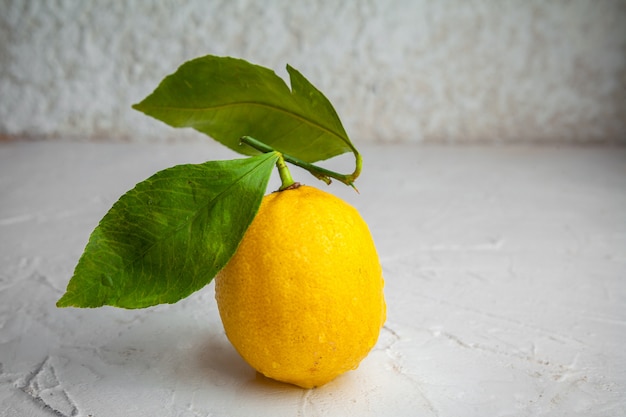 Vista lateral de limón con hojas sobre fondo blanco con textura. horizontal