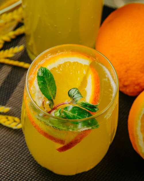 Vista lateral de limonada de cítricos en rodajas de naranja agua con gas menta