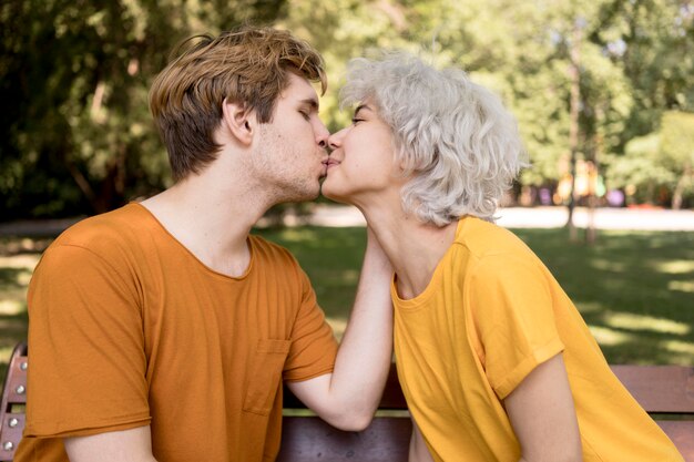 Vista lateral de la linda pareja compartiendo un beso en el parque