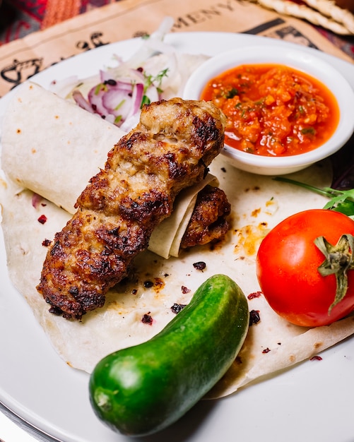 Vista lateral de lula kebab en pan de pita con verduras y salsa