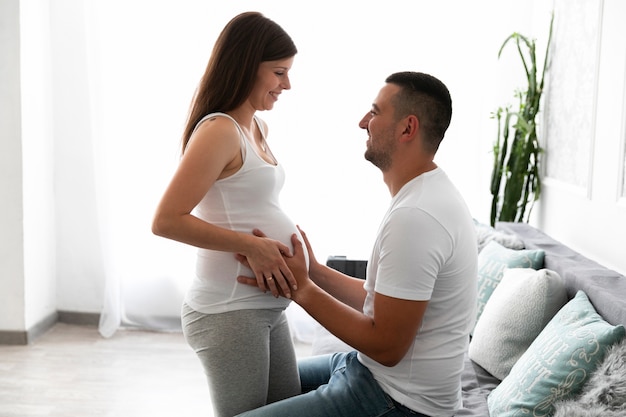 Vista lateral madre y padre esperando un nuevo miembro de la familia