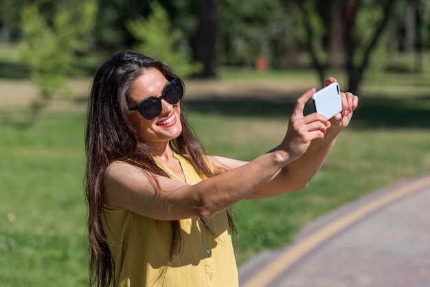 Vista lateral de la madre tomando fotografías de su familia con el smartphone mientras está al aire libre