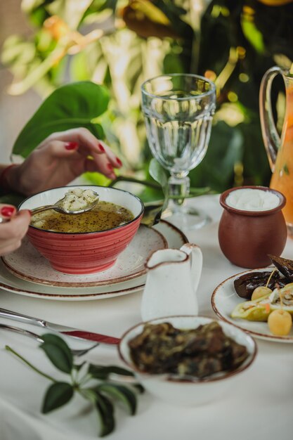 Vista lateral de la mano femenina con una cuchara de sopa de albóndigas dushbara