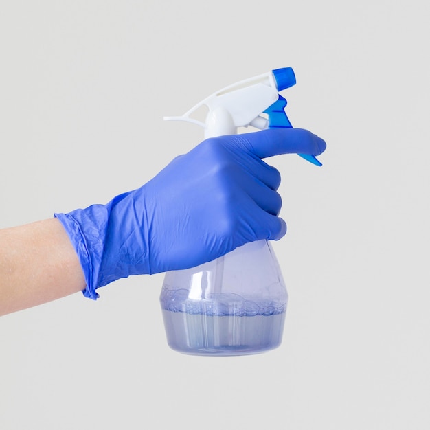 Foto gratuita vista lateral de la mano con guante quirúrgico sosteniendo una botella de ablución