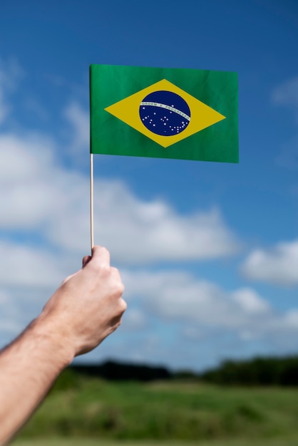 Foto gratuita vista lateral mano que sostiene la bandera brasileña