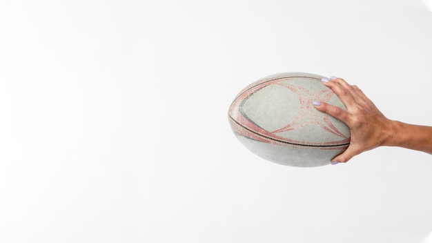 Vista lateral de la mano que sostiene la pelota de rugby con espacio de copia