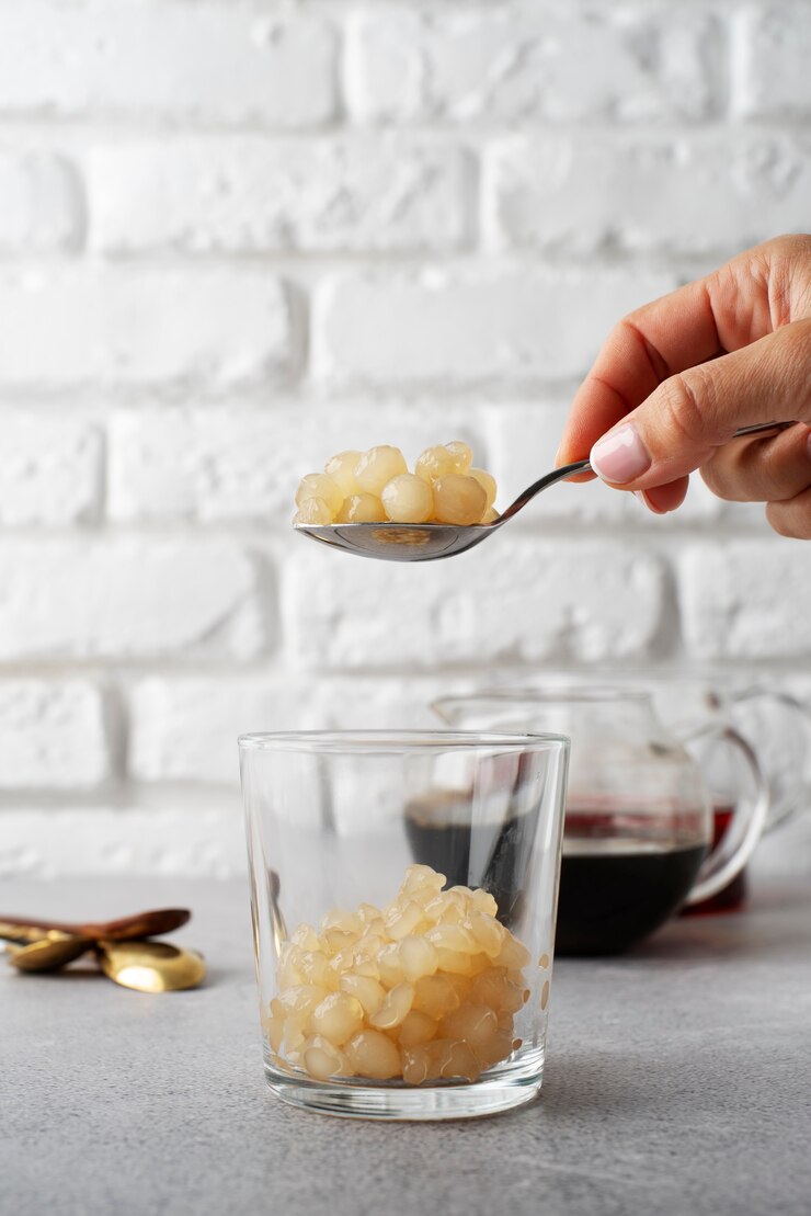 Foto gratuito vista lateral mano sosteniendo una cuchara con bolas de tapioca
