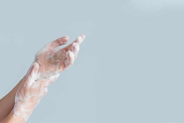 Vista lateral de manos cubiertas de espuma de jabón
