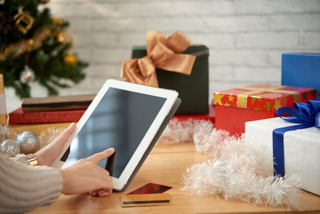 Vista lateral de manos femeninas comprando regalos para Navidad en línea