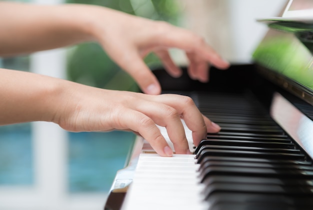 Vista lateral de las manos de una mujer tocando el piano