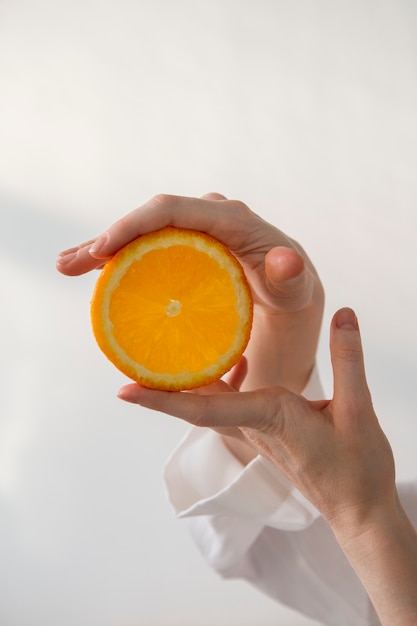 Vista lateral manos sosteniendo rodaja de naranja