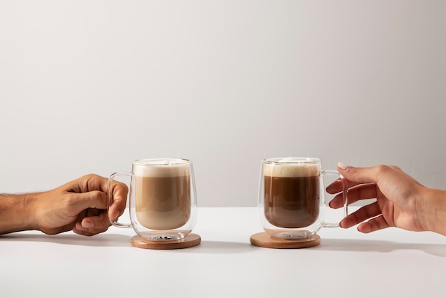 Vista lateral manos sosteniendo tazas de café