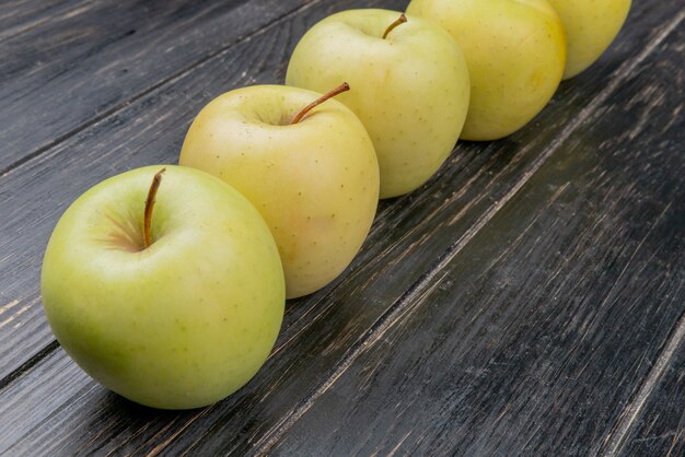vista lateral de manzanas amarillas sobre fondo de madera