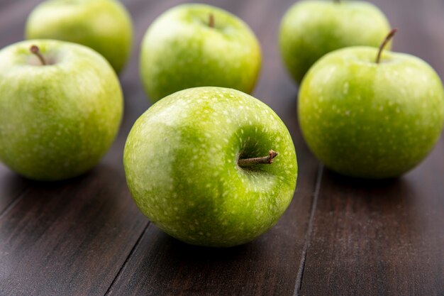 Vista lateral de manzanas frescas y verdes aisladas sobre una superficie de madera