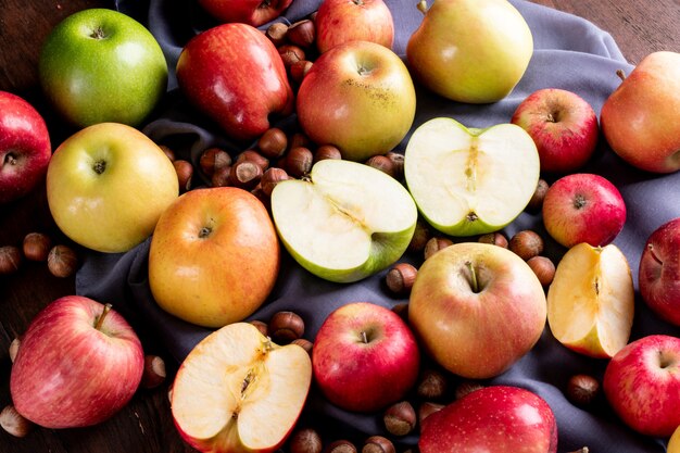Vista lateral de manzanas con nueces sobre tela gris horizontal