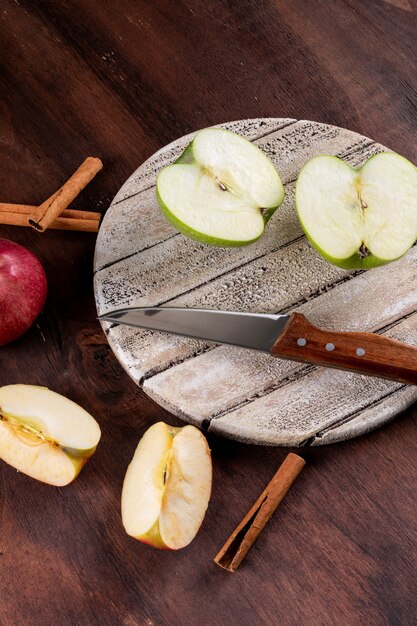 Vista lateral de las manzanas en rodajas con un cuchillo en la pizarra blanca vertical