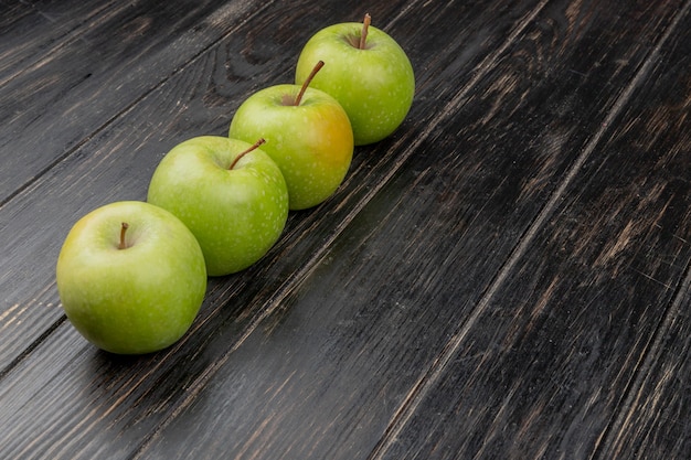 Vista lateral de manzanas verdes sobre superficie de madera