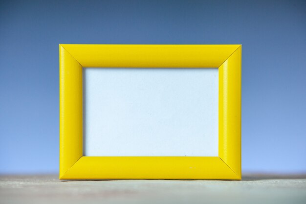 Vista lateral del marco de imagen vacío amarillo de pie sobre una mesa blanca sobre la superficie de la onda azul con espacio libre