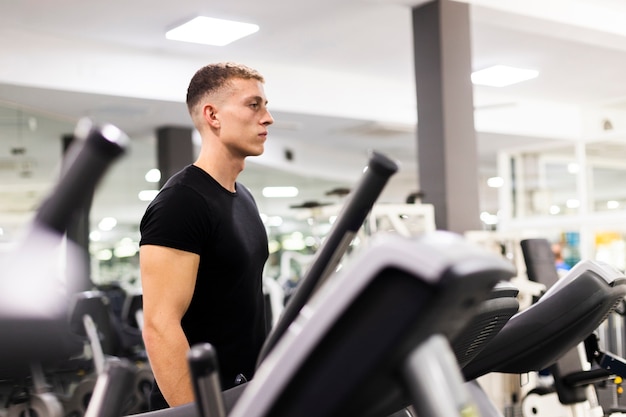 Vista lateral masculino joven en el entrenamiento de gimnasio